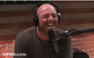 A Man Wearing Headphones Is Laughing While Sitting In Front Of A Microphone . GIF