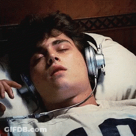 A Man Wearing Headphones Is Laying In Bed GIF