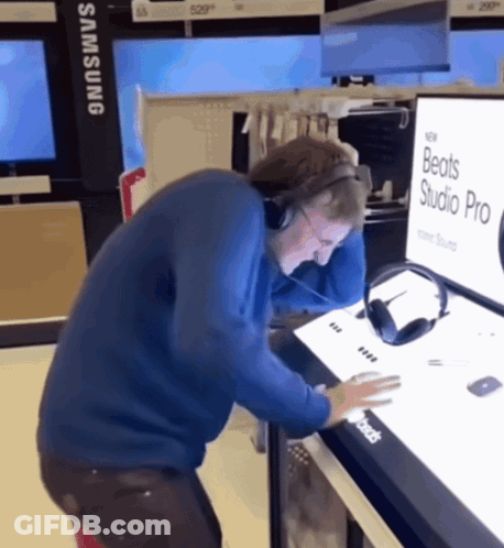 A Man Wearing Headphones Is Looking At A Display For Beats Studio Pro GIF