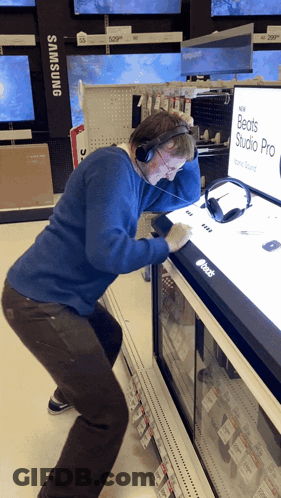 A Man Wearing Headphones Is Looking At A Display Of Beats Studio Pro Headphones GIF