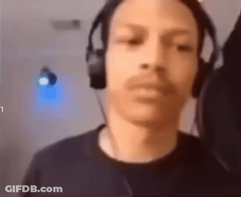 A Man Wearing Headphones Is Looking At The Camera And Making A Funny Face . GIF