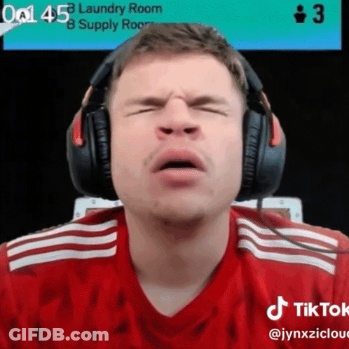 A Man Wearing Headphones Is Making A Face In Front Of A Laundry Room Sign GIF