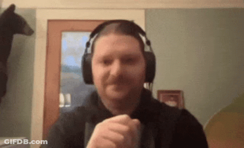 A Man Wearing Headphones Is Making A Fist In Front Of A Bear . GIF