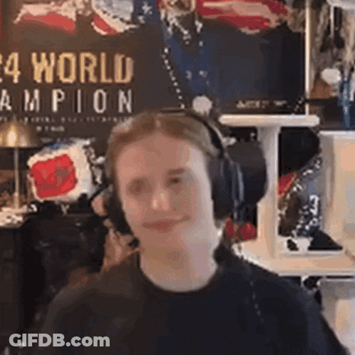 A Man Wearing Headphones Is Making A Funny Face In Front Of A Wall With A Poster On It . GIF