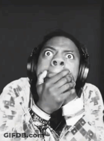 A Man Wearing Headphones Is Making A Funny Face While Covering His Mouth . GIF