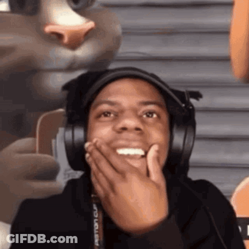 A Man Wearing Headphones Is Making A Funny Face While Holding His Hand To His Face . GIF