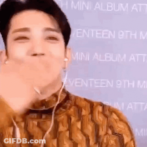 A Man Wearing Headphones Is Making A Funny Face While Holding His Hand To His Mouth . GIF