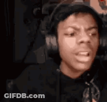 A Man Wearing Headphones Is Making A Funny Face While Sitting In A Chair . GIF