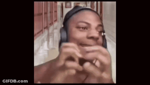A Man Wearing Headphones Is Making A Funny Face While Standing In A Hallway . GIF