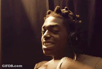A Man Wearing Headphones Is Making A Funny Face While Touching His Teeth . GIF