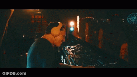A Man Wearing Headphones Is Playing A Dj Set At A Party GIF