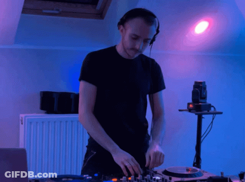 A Man Wearing Headphones Is Playing A Record On A Turntable GIF
