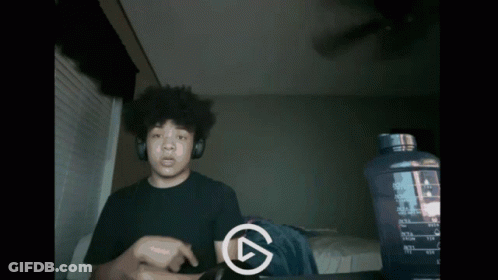 A Man Wearing Headphones Is Playing A Video With A Play Button In The Corner GIF