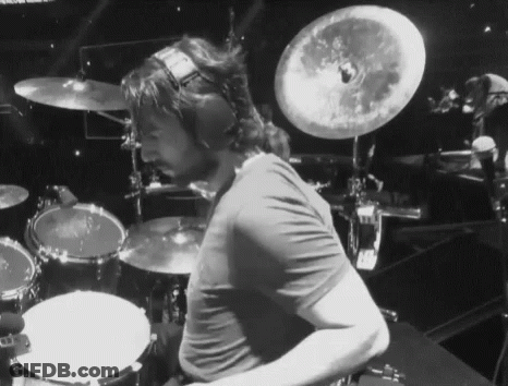 A Man Wearing Headphones Is Playing Drums On A Stage GIF
