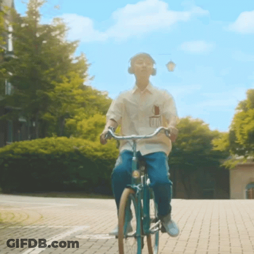 A Man Wearing Headphones Is Riding A Bicycle On A Brick Road GIF