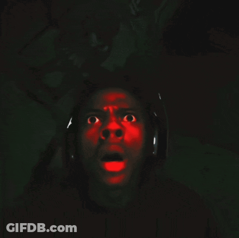 A Man Wearing Headphones Is Screaming With A Red Light Projected On His Face GIF