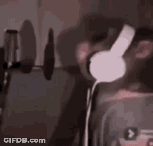 A Man Wearing Headphones Is Singing Into A Microphone In A Dark Room . GIF