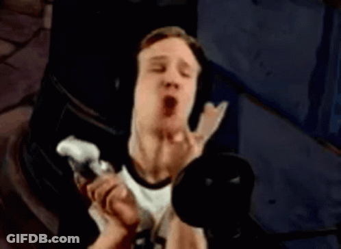 A Man Wearing Headphones Is Singing Into A Microphone In A Dark Room . GIF
