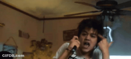 A Man Wearing Headphones Is Singing Into A Microphone In Front Of A Sign That Says Route 66 GIF