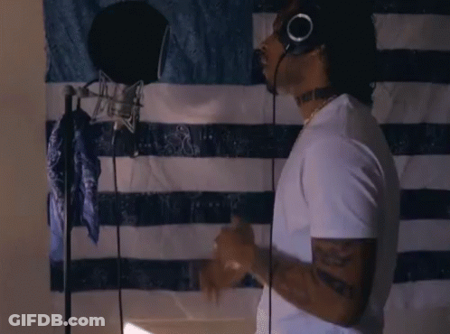A Man Wearing Headphones Is Singing Into A Microphone GIF