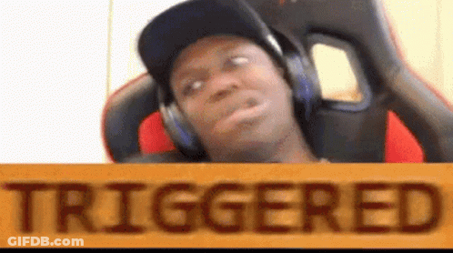 A Man Wearing Headphones Is Sitting In A Chair With A Sign That Says Triggered . GIF