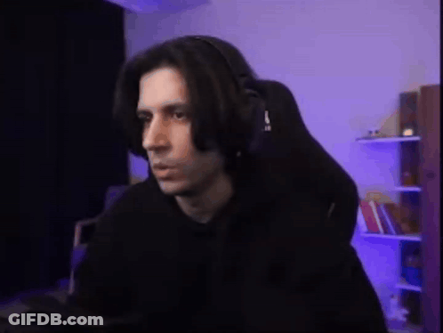 A Man Wearing Headphones Is Sitting In A Gaming Chair In Front Of A Computer . GIF