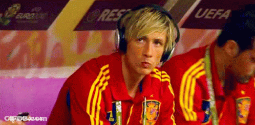 A Man Wearing Headphones Is Sitting In A Locker Room With Uefa Written On The Wall Behind Him GIF