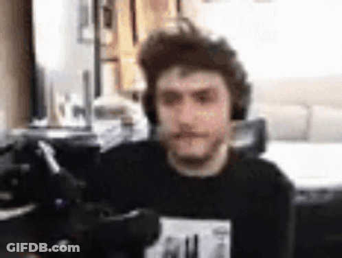 A Man Wearing Headphones Is Sitting In Front Of A Computer Screen . GIF