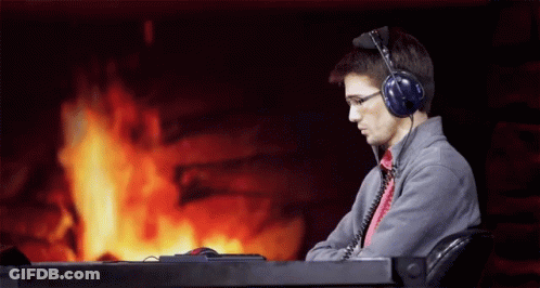 A Man Wearing Headphones Is Sitting In Front Of A Fireplace GIF