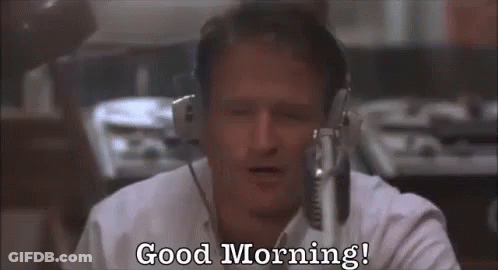 A Man Wearing Headphones Is Sitting In Front Of A Microphone And Says `` Good Morning '' . GIF