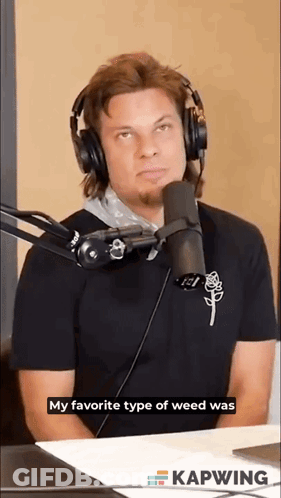 A Man Wearing Headphones Is Sitting In Front Of A Microphone And Talking Into It . GIF