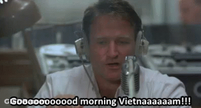 A Man Wearing Headphones Is Sitting In Front Of A Microphone And Talking Into It . GIF