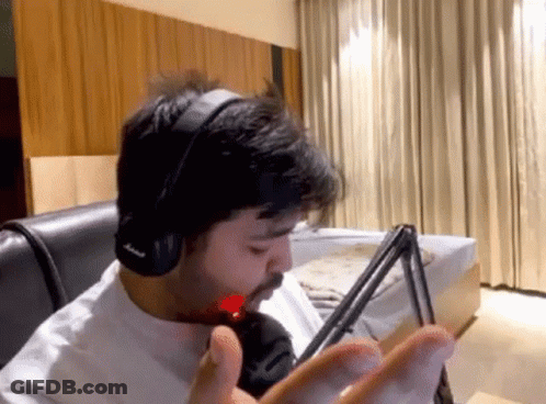 A Man Wearing Headphones Is Sitting In Front Of A Microphone In A Living Room . GIF