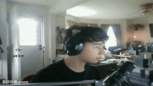 A Man Wearing Headphones Is Sitting In Front Of A Microphone In A Room GIF