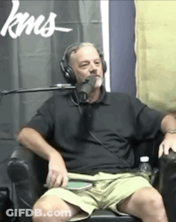 A Man Wearing Headphones Is Sitting In Front Of A Microphone In Front Of A Sign That Says Kns GIF
