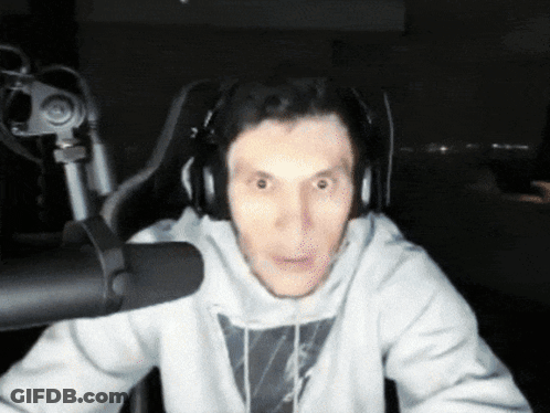 A Man Wearing Headphones Is Sitting In Front Of A Microphone Making A Funny Face GIF