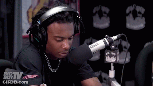 A Man Wearing Headphones Is Sitting In Front Of A Microphone That Says Big Tv On It GIF