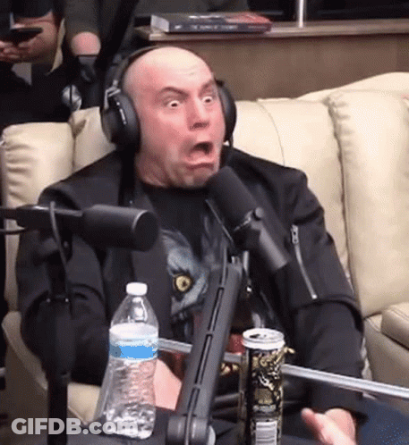 A Man Wearing Headphones Is Sitting In Front Of A Microphone With A Can Of Soda And A Bottle Of Water . GIF