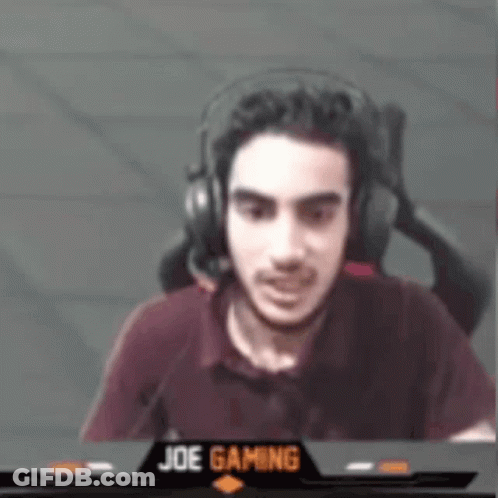 A Man Wearing Headphones Is Sitting In Front Of A Screen That Says Joe Gaming On It . GIF