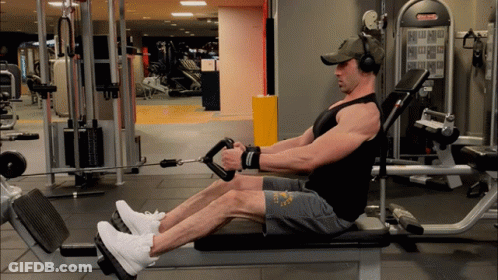A Man Wearing Headphones Is Sitting On A Bench In A Gym With A Machine That Says ' Matrix ' On It GIF