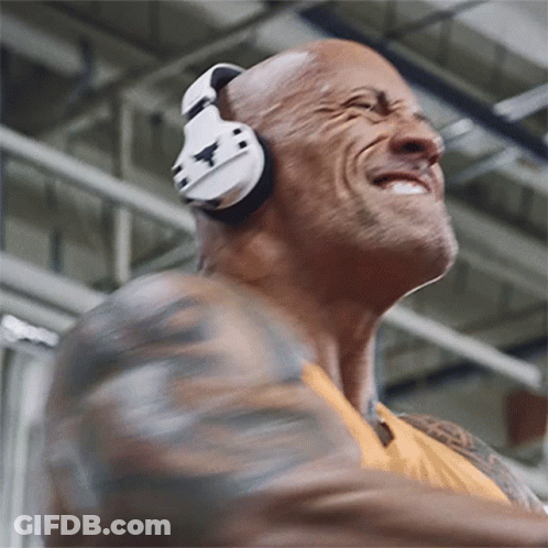 A Man Wearing Headphones Is Smiling And Dancing In A Gym GIF
