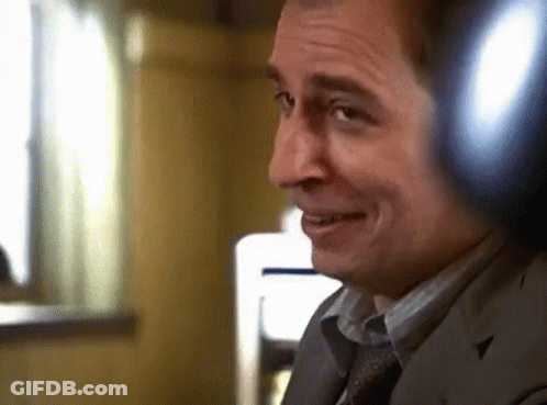 A Man Wearing Headphones Is Smiling And Looking At The Camera GIF