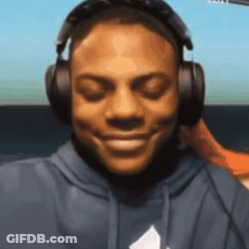 A Man Wearing Headphones Is Smiling And Looking At The Camera GIF