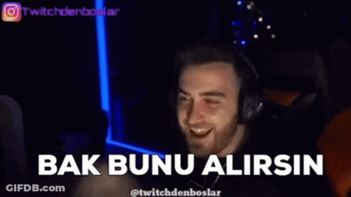 A Man Wearing Headphones Is Smiling And Pointing At The Camera In A Dark Room . GIF