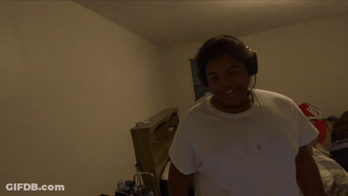 A Man Wearing Headphones Is Standing In A Room GIF