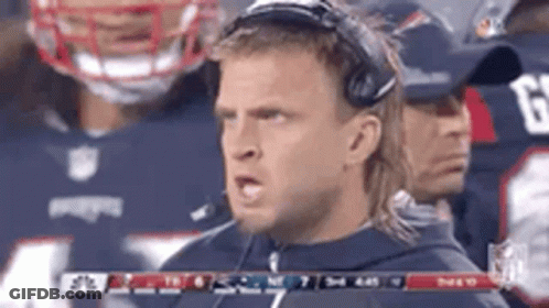 A Man Wearing Headphones Is Standing In Front Of A Football Team . GIF