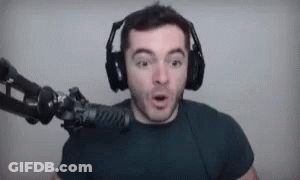 A Man Wearing Headphones Is Standing In Front Of A Microphone And Making A Funny Face . GIF