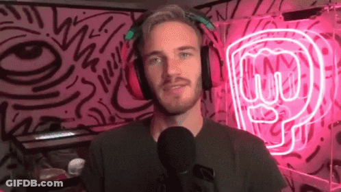 A Man Wearing Headphones Is Standing In Front Of A Microphone In Front Of A Neon Sign That Says P GIF