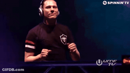 A Man Wearing Headphones Is Standing In Front Of A Screen That Says Spinnin ' Tv . GIF