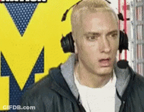 A Man Wearing Headphones Is Standing In Front Of A Yellow M GIF